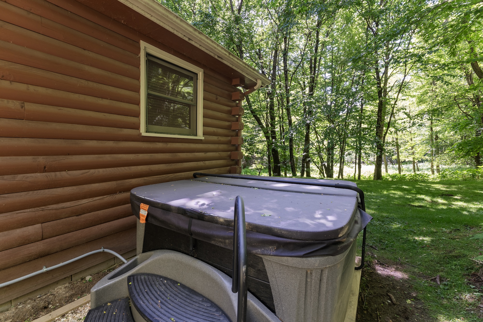 Private hot tub beside log cabin with wooded surroundings